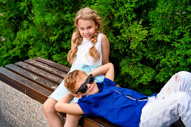 Little children are relaxing on a bench. Fashion concept. Summer. - Foto, afbeelding