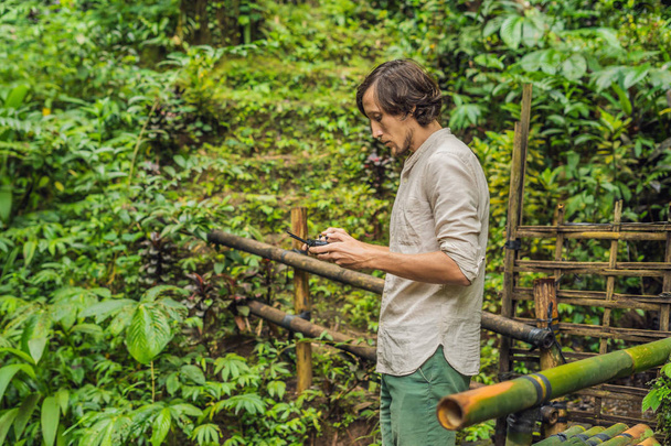 Man controlling drone with tropical plants at background  - Fotó, kép