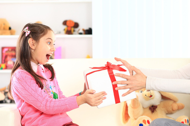 Little beautiful pretty girl giving a gift to her happy mother - 写真・画像