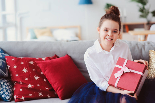 happy kid girl with gift for birthday or christmas posing at home in modern scandinavian interior, preparing or unwraping holiday gift. - Foto, Imagen