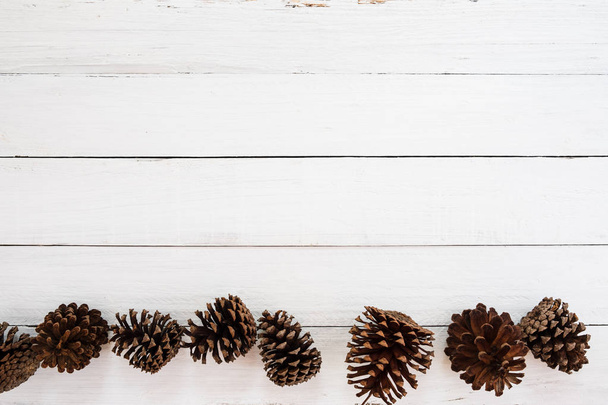 Sfondo rustico natalizio con pigna su legno bianco. stile minimale, vista dall'alto, bordo
. - Foto, immagini