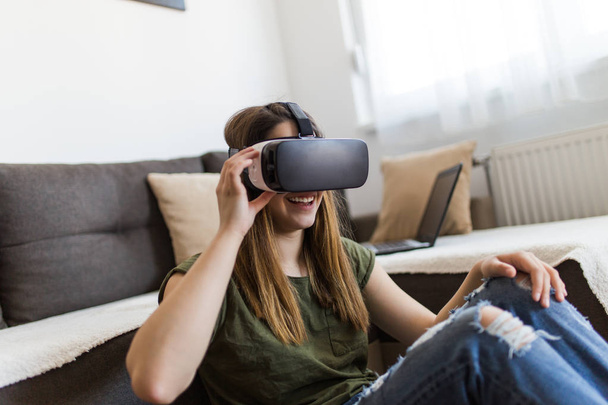 Beautiful young woman enjoying virtual reality at her home. - Foto, Imagen
