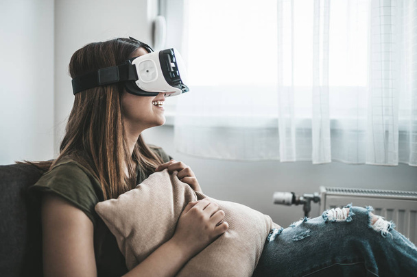 Beautiful young woman enjoying virtual reality at her home. - 写真・画像