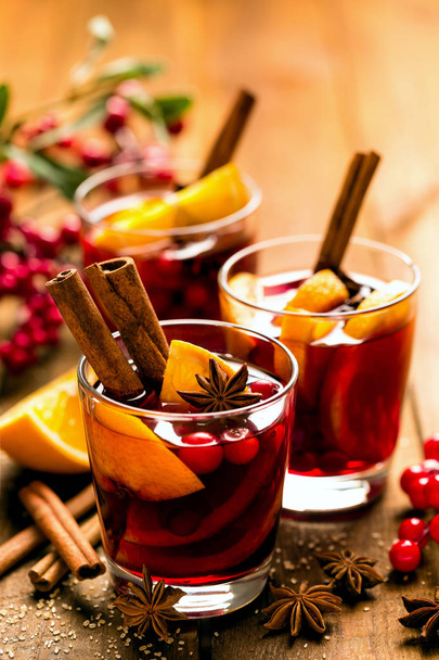 Christmas mulled red wine with spices and oranges on a wooden rustic table. Traditional hot drink at Christmas - Zdjęcie, obraz