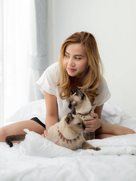 Happy Asian woman and her cats on bed. - Foto, Imagem