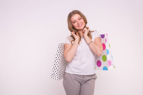 Concepto de personas, venta y consumismo Atractiva joven rubia sosteniendo bolsas multicolores sobre fondo blanco con espacio para copiar
 - Foto, imagen