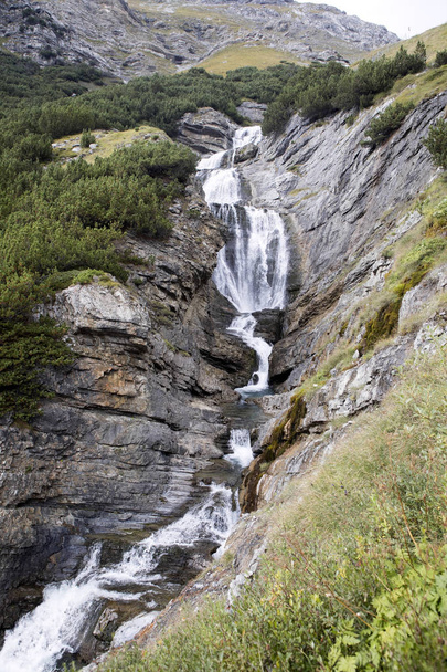 waterfall below the summit of a mountain road Stelvio, Italy - Фото, изображение
