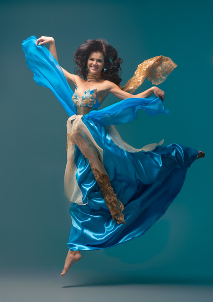 beautiful girl floating in mid-air, blue silk dress - Photo, image