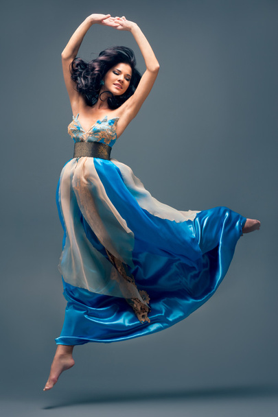 beautiful girl floating in mid-air, blue silk dress - Фото, зображення