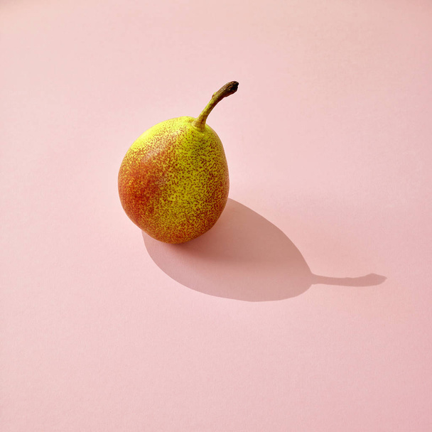 verse peren met lange schaduw op roze papieren achtergrond - Foto, afbeelding