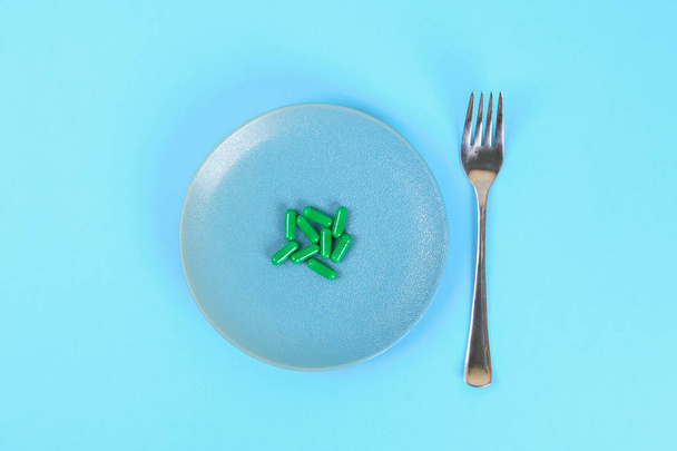 Eating pills as a regular meal. Pills on a plate on a blue table background. Top view, copy space, flat lay - Foto, Bild
