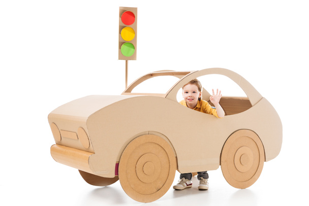 adorable boy waving and playing with cardboard car and traffic lights on white - Photo, Image