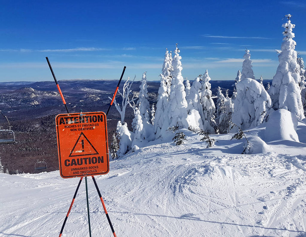Señal de precaución y advertencia en una estación de esquí sobre rocas y obstáculos sin marcar en el comienzo de un sendero
. - Foto, imagen