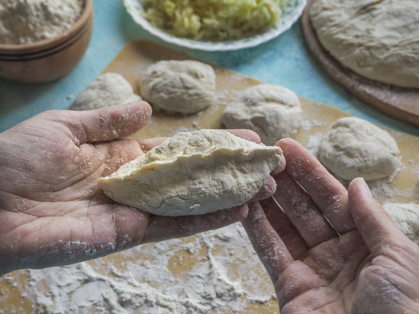 A small pie of raw dough in the cook's hands. - Photo, Image