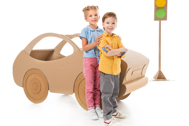 happy children posing near cardboard car and traffic lights, on white - Foto, afbeelding
