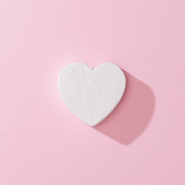 Witte hart op roze achtergrond, minimale liefde. Plat leggen  - Foto, afbeelding