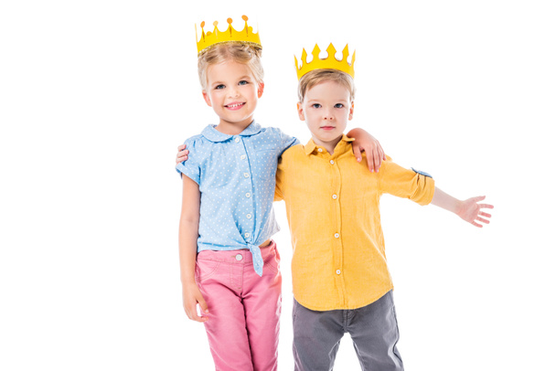 adorable kids in yellow paper crowns hugging and looking at camera, isolated on white - Foto, Imagem