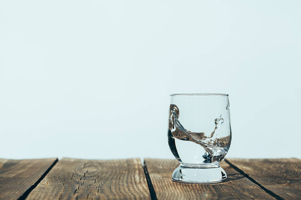 un chorrito de agua en un vaso sobre madera
 - Foto, imagen