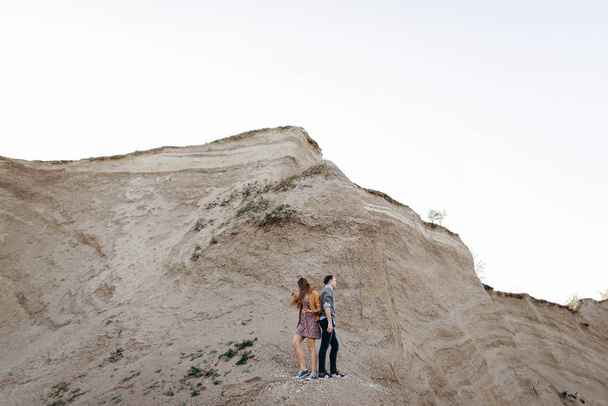 Lovely couple walking together at foot of cliff - Photo, image