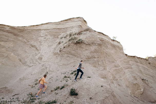 素敵なカップルが一緒に崖の麓を歩く - 写真・画像