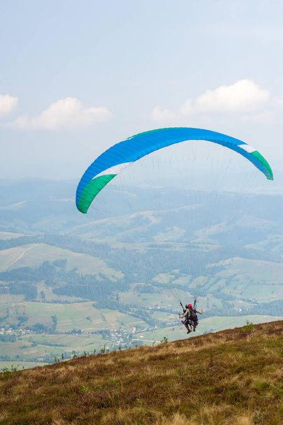Der Gleitschirm hebt vom Berghang in den Karpaten ab. Paragliding in den Bergen im Sommer. - Foto, Bild