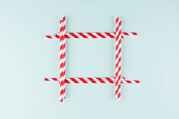 Minimalist modern art abstract background - red striped straws on light soft mint colors paper as blank square frame. - Foto, afbeelding