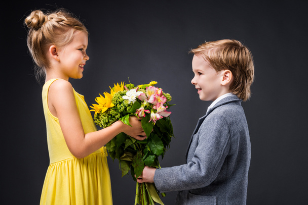 little smiling couple with bouquet of flowers, isolated on grey - Foto, Bild