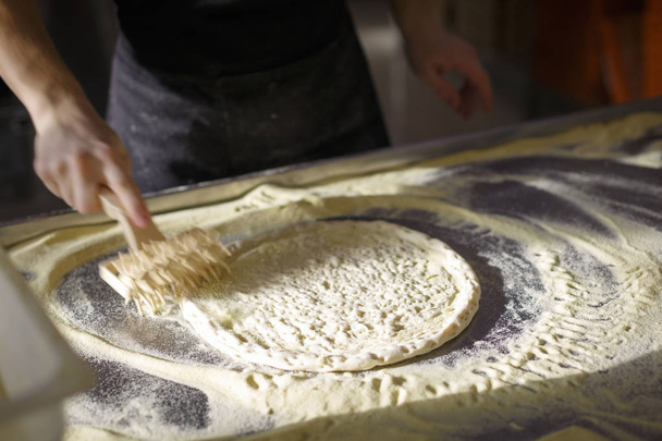 Baker prepara la base de pizza para que sea porosa
 - Foto, Imagen