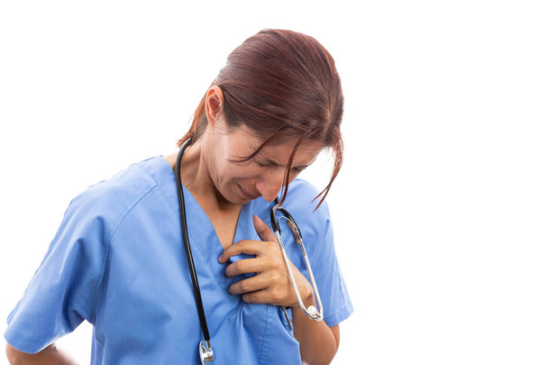 Enfermeira feminina exausta agarrando área cardíaca dolorosa com a mão como conceito de doença cardíaca ataque cardíaco isolado em fundo branco
 - Foto, Imagem