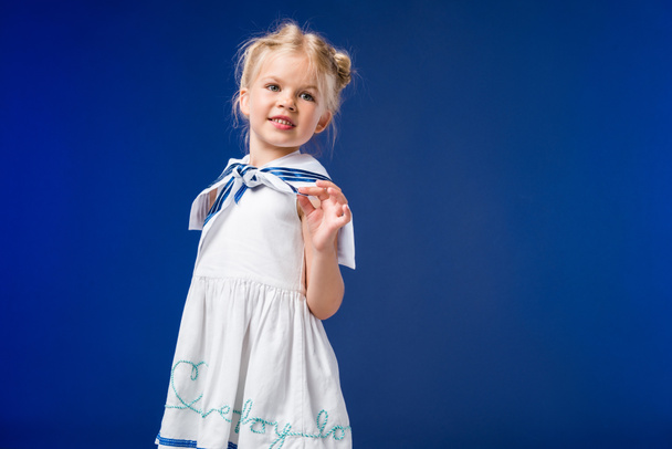 schattige blonde kind poseren in matroos kostuum, geïsoleerd op blauw - Foto, afbeelding