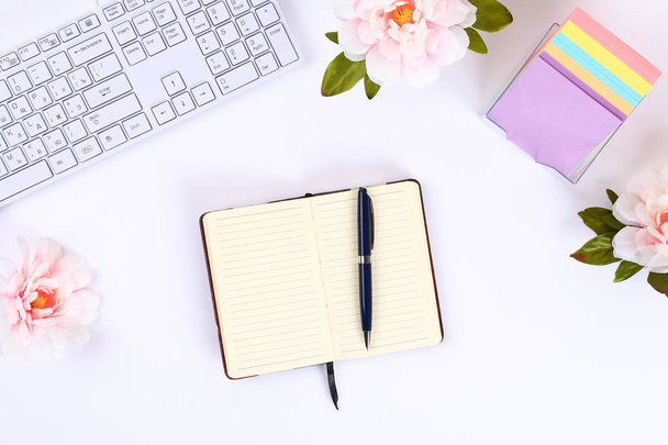 A blank white notepad on a white desktop next to a coffee mug and a keyboard. Top view, flat layout. Copy the space - Photo, Image