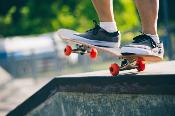 Skateboarder legs riding on skateboard in the skatepark - Fotó, kép