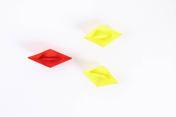 Red paper boat among other white. Leadership, white crow, individuality. Piranhas and a shark. Not like everyone else. Origami. Top view, flat lay, copy space - Photo, image