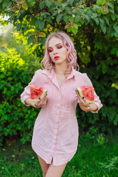 Beautiful young woman with pink hair holding two slices of sweet juicy watermelon - Φωτογραφία, εικόνα