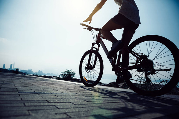 Hands free cycling woman riding Mountain Bike on sunrise seaside - Foto, Bild