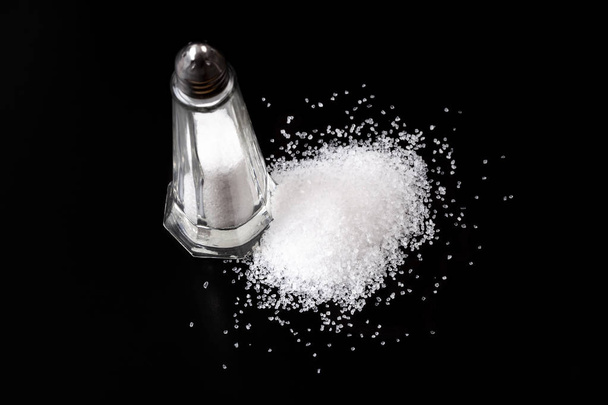 Biała sól Shaker z solą stos na czarnym tle - Zdjęcie, obraz