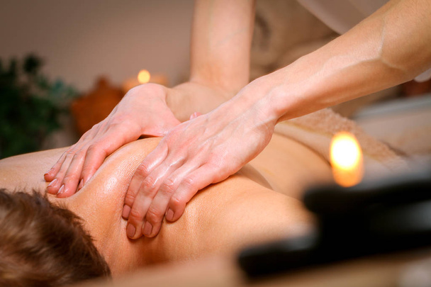 Молодой человек получает массаж плеч и спины от терапевта в спа
 - Фото, изображение