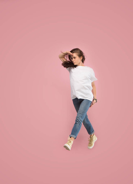 Freedom in moving. Pretty young woman jumping against pink background - Photo, image