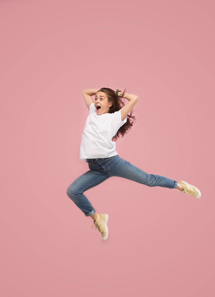 Freedom in moving. Pretty young woman jumping against pink background - Foto, immagini