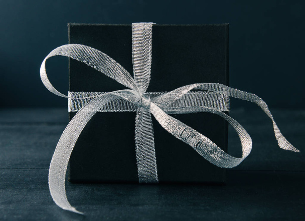 schwarze Geschenkschachtel mit silberner Schleife auf schwarzem Hintergrund. Tonne Foto. - Foto, Bild