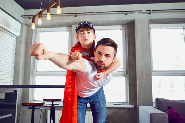 Father and daughter kid in suits super hero play in the room. - 写真・画像