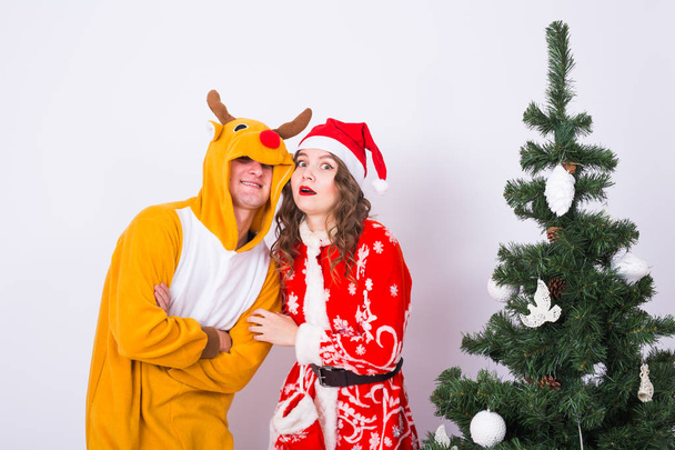 Urlaub, Humor, Menschenkonzept - glückliche junge Frau mit Weihnachtsmann-Hut und Mann im Faschingskostüm aus Hirschen - Foto, Bild