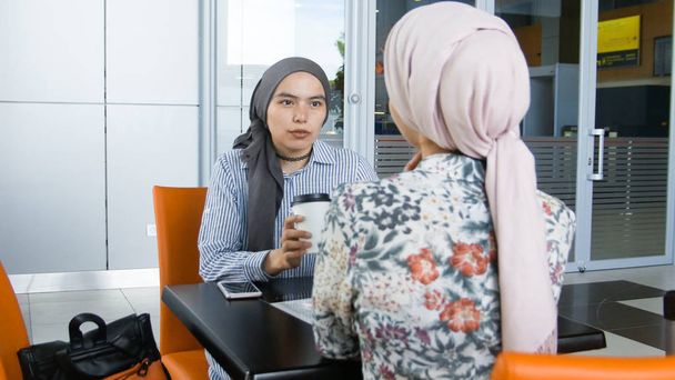 コーヒーを飲むと話している 2 つのイスラム教徒の女の子 - 写真・画像