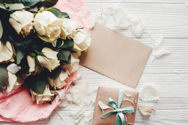 Rosas blancas con tarjeta vacía y caja de regalo sobre fondo de madera, espacio para texto. Tarjeta de felicitación floral maqueta. Invitación a la boda, feliz día de la madre. San Valentín
 - Foto, Imagen