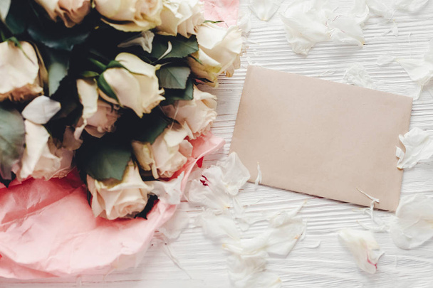 Rosas blancas con tarjeta vacía sobre fondo de madera, plano yacía con espacio para el texto. Tarjeta de felicitación floral maqueta. Invitación a la boda, feliz día de la madre. San Valentín
 - Foto, imagen