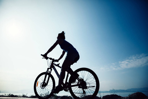 Cycling woman riding mountain mike on sunrise seaside  - Zdjęcie, obraz