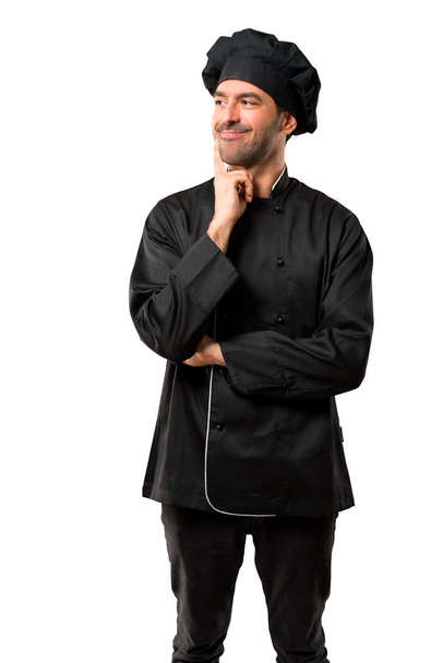 Kokkimies mustassa univormussaan seisoo ja ajattelee ideaa katsoessaan ylös eristettyä valkoista taustaa
 - Valokuva, kuva