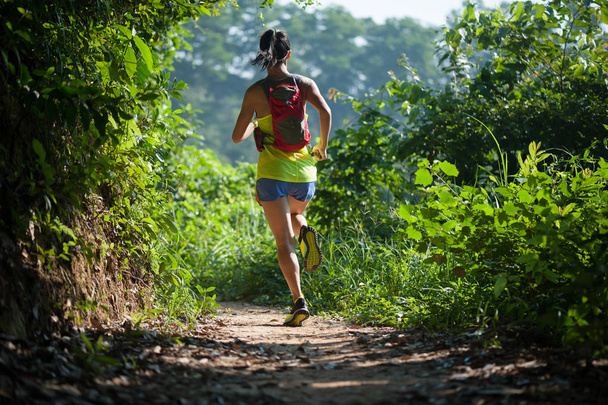 Corredor de senderos de mujer joven corriendo por sendero de bosque tropical durante la mañana
 - Foto, imagen