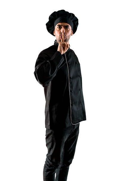 Σεφ άνθρωπος στην μαύρη στολή δείχνει ένα σημάδι της κλείνοντας το στόμα και σιωπή χειρονομία σε απομονωμένες άσπρο φόντο - Φωτογραφία, εικόνα