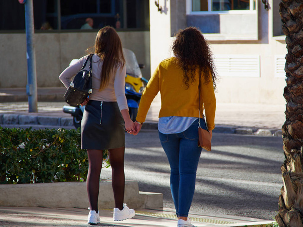 Two Lesbian gay girls women holding each other hands while walking in the street - Fotoğraf, Görsel